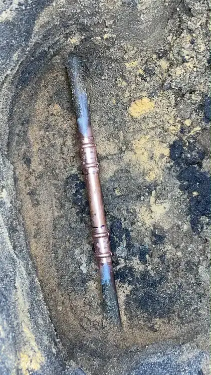 A repaired copper water line exposed in a small dig.